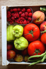 Wooden crate full of healthy seasonal fruit and vegetable. Top view, wooden background.