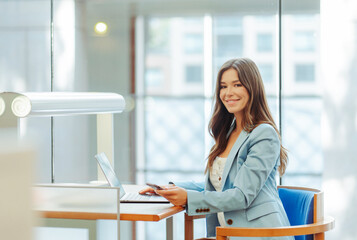 Confident smiling businesswoman, manager, designer using laptop working online looking at camera ...