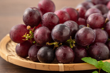 Delicious bunch of grapes fruit on a plate over wooden table background.