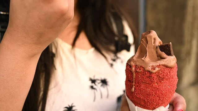 Tourist woman is trying traditional Trdelnik or trdlo Czech sweet. Woman holding trdlo in Prague street. Street food. Trdelnik is a traditional sweet cake with sugar and cinnamon with Bread. 4K.