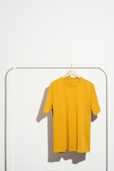 Yellow t-shirt on wooden hanger displayed on a clothes rack