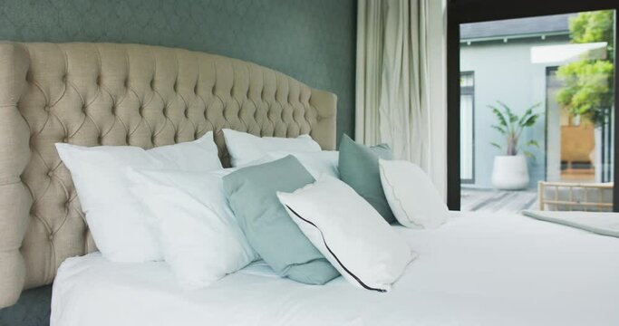 General view of bed with white sheets, big window and view to garden in bedroom, slow motion