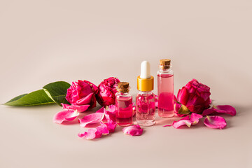 Obraz na płótnie Canvas A set of cosmetics based on rose oil in various bottles among the buds of small roses on a beige background. home care