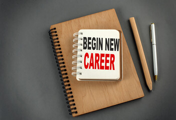 BEGIN NEW CAREER text on notebook with pen and pencil on grey background