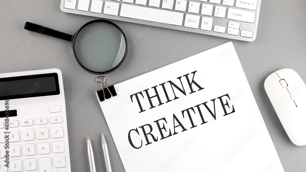 Poster think creative written on paper with office tools and keyboard on the grey background