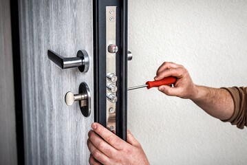 Handyman repair the door lock in metal entrance door, Man fixing lock with screwdriver