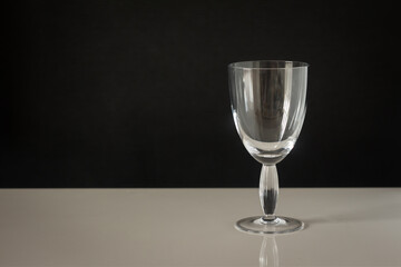 a large glass with a thick stem on a dark background and a white table