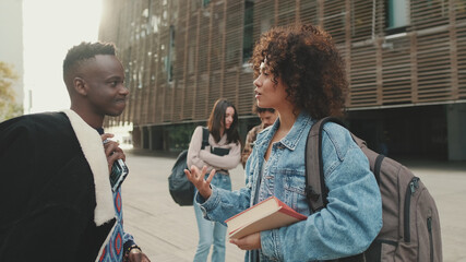 Student couple chatting while standing on the street