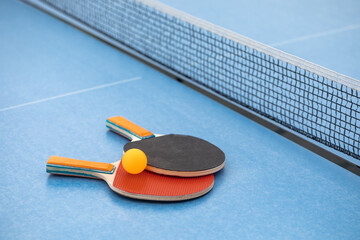 Table tennis. Blue ping pong table. Ping pong rackets and ball. The concept of sport and healthy...