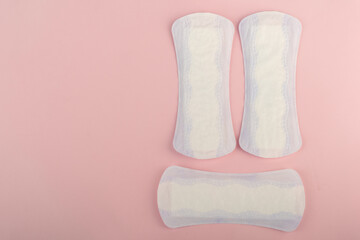 Purple and white feminine sanitary pads on a pink background with space for text.