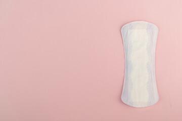 Fototapeta na wymiar Top view of one purple and white women's sanitary menstrual pad on a pink background with space for text.