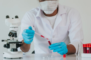 Medical science laboratory: Portrait of a scientist looking under a microscope analyzing a test sample. Works with advanced devices