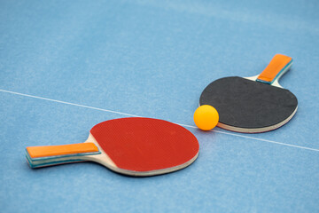 Table tennis. Blue ping pong table. Ping pong rackets and ball. The concept of sport and healthy...