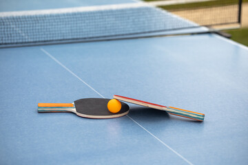 Table tennis. Blue ping pong table. Ping pong rackets and ball. The concept of sport and healthy...