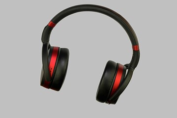 Wireless stereo headset. Black and red cordless headphones. Earphones isolated on grey background with clipping path. Macro horizontal image, close-up.