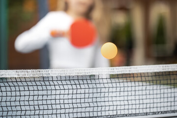 The girl plays table tennis. A girl hits a table tennis ball with a racket. Submission of the ball. Sport games. Sport lifestyle concept. - obrazy, fototapety, plakaty