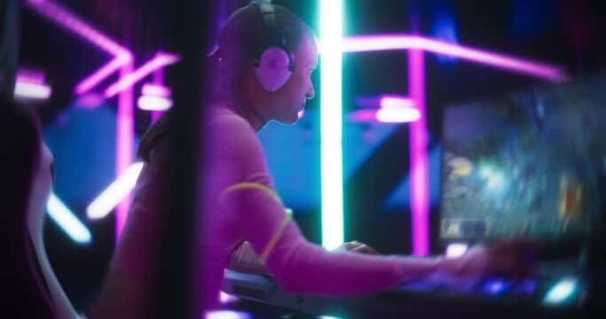 Portrait of a Happy Girl Focused on Playing an Online Video Game on a Computer. Stylish Gamer Playing Games in a Futuristic Neon Studio Room. 360 Degree Moving Around Footage with Zoom In Effects
