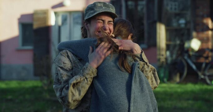 Slow Motion Portrait of Young Happy Female Soldier Receiving her Daughter with Open Arms After Returning Back Home From a Mission. Mother in Camouflage Military Uniform Hugging and Kissing her Girl