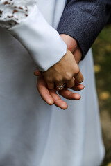 wedding couple walks outside in autumn nature with a view of a wooden house. a young bride with a...