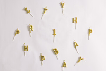 Top view of gold happy birthday letter candles and number one gold candle for first birthday disorderly placed. Birthday party ideas.