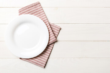 Top view on colored background empty round white plate on tablecloth for food. Empty dish on napkin with space for your design