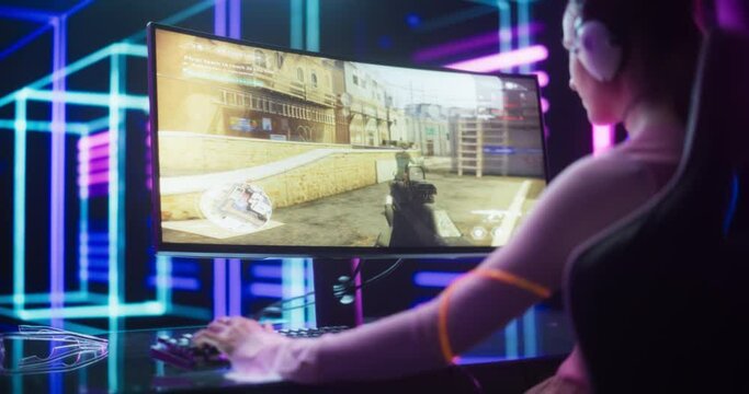 Over the Shoulder Footage of a Young Excited Gamer Smashing Competition in a First Person Shooter Game. Stylish Young Female Focused on a Online Team Playing Event in a Futuristic Neon Room
