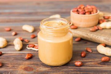 Bowl of peanut butter and peanuts on table background. top view with copy space. Creamy peanut...