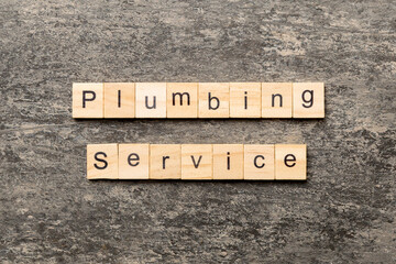Fototapeta premium Plumbing service word written on wood block. Plumbing service text on cement table for your desing, concept