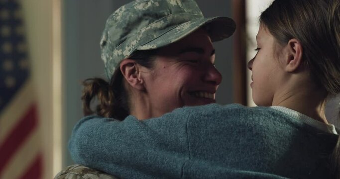 Slow Motion Portrait of Young Happy Female USA Soldier Hugging and Kissing her Daughter After Returning Back Home From a Mission. Mother in Camouflage Military Uniform Showing Affection, Crying