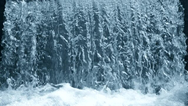 Beautiful natural waterfall background with falling crystalline water flow and splashing drops with foam. Scene with blue and cyan color, perspective, mid shot, super slow motion, hd. ProRes 422 HQ.