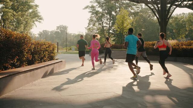 Multiracial young runners run in green park of big city