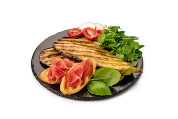 Grilled spicy eggplants on a black plate, isolated on white background.