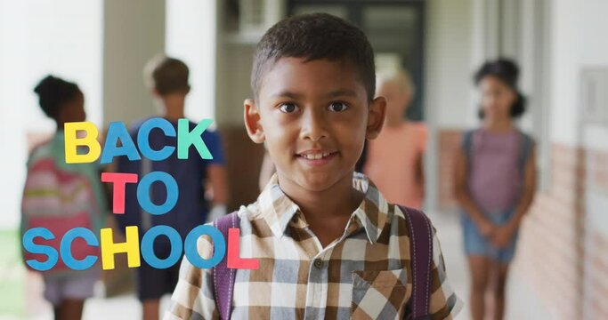 Animation of back to school text over happy biracial schoolboy at school