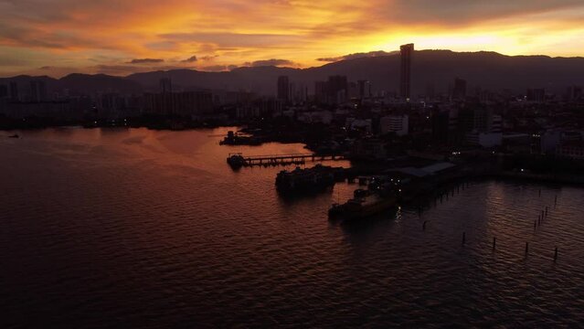 Penang, Malaysia: Aerial drone footage of the Georgetown seafront area with the ferry terminal and the ancient Clan jetty, wooden stilt houses for Chinese immigrants at sunset.  