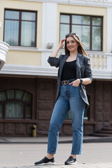 Portrait of a happy smiling woman in casual clothes while walking around the city.