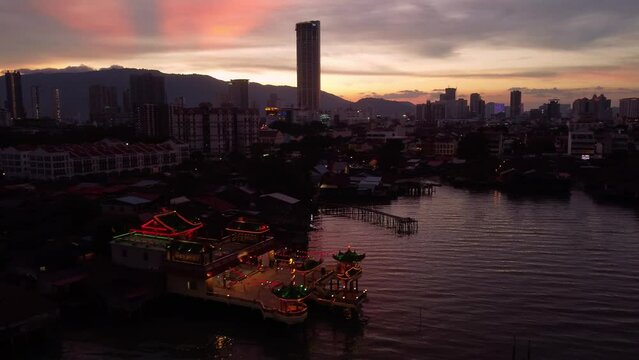 Penang, Malaysia: Aerial drone footage of the Georgetown seafront area with Kuan Yin Floating Temple and the ancient Clan jetty, wooden stilt houses for Chinese immigrants at sunset.  