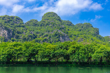 Fototapeta na wymiar Trang An River Ninh Minh and Bai Dinh Mountain ranges in Vietnam only 3 hours drive from Hanoi. Beautiful winding river and large rising mountains. boats going through the caves in the river