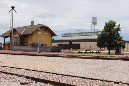Bertram, TX - June 8, 2023: Historic Train Depot with Library in Background on Cloudy Day in Bertram Texas