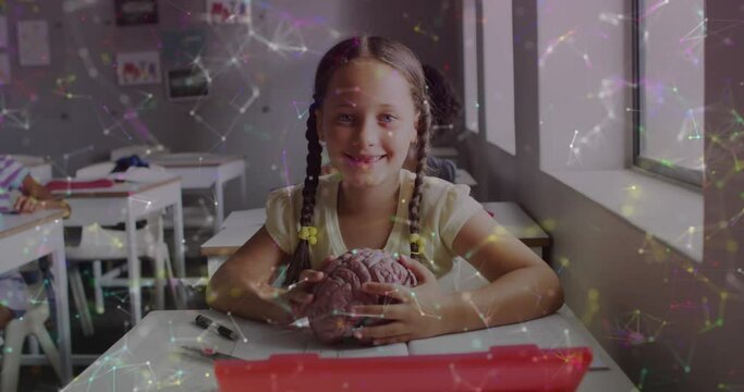 Animation of networks over happy biracial schoolgirl at desk holding model brain