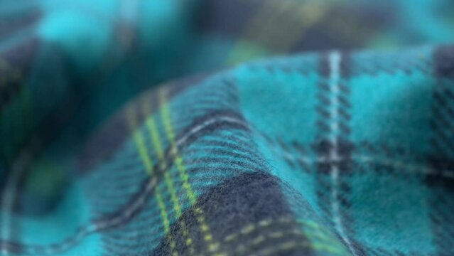 closeup of a crumpled cozy flannel fabric with a blue checkered pattern. slow rotation of soft cotton fabric. macro. fabric background textile production.