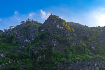 Naklejka premium Dragon Mountain in Ninh Binh Hanoi Vietnam with over 500 zigzag steps to climb to the top with magnificent views of a big dragon on the mountain peak and a small temple 