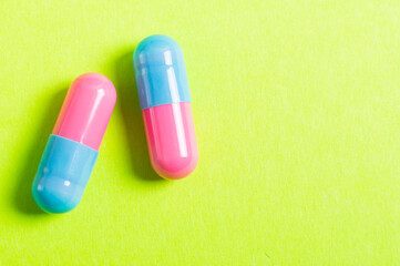 Pills on the green background, pink and blue colors. Medical concept