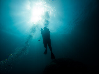 Diver silhouette and bubbles in deep water.