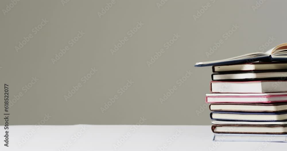 Aufkleber close up of open book on stack of books with copy space on grey background, in slow motion