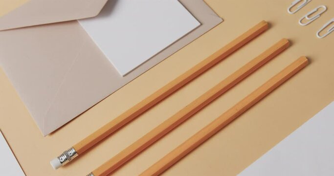 Flat lay of pencils, envelope and memo note with copy space on yellow background