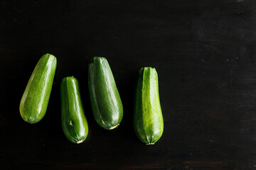 four green fresh zucchini on a black background. Concept of healthy eating