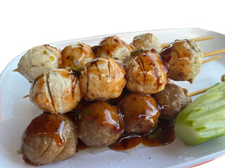 appetizer menu Fried meatballs topped with delicious dipping sauce. There is cucumber as a side dish.