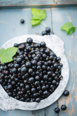 Ripe black currants in a vintage metal tray on a wooden background, top view