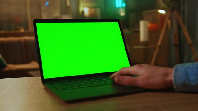 Close up hands of freelancer use laptop with green screen. At home. Working. Scrolling through website