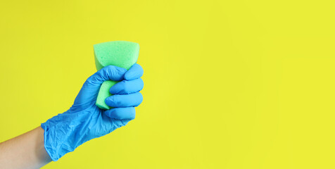 A woman's hand in a blue glove squeezes a sponge for washing dishes. House cleaning. A hand with a...